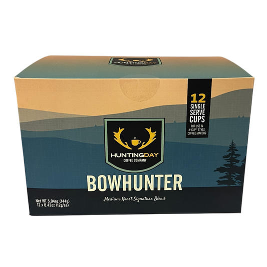 A box of Huntingday Bowhunter Medium Beef Signature Blend coffee, featuring a mountain landscape graphic in teal, beige, and black with a central hunting logo.
