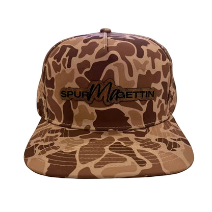 A brown and tan camouflage snapback cap with a black embroidered 'SPURMAGETTIN' logo on the front