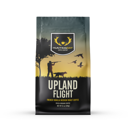 A bag of Huntingday Coffee Company Upland Flight French Vanilla Medium Roast Coffee, featuring a black and yellow graphic design with a hunting silhouette and birds.